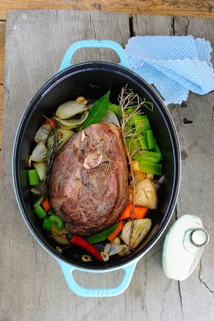 Leg of lamb with vegetables and herbs in a braising pot