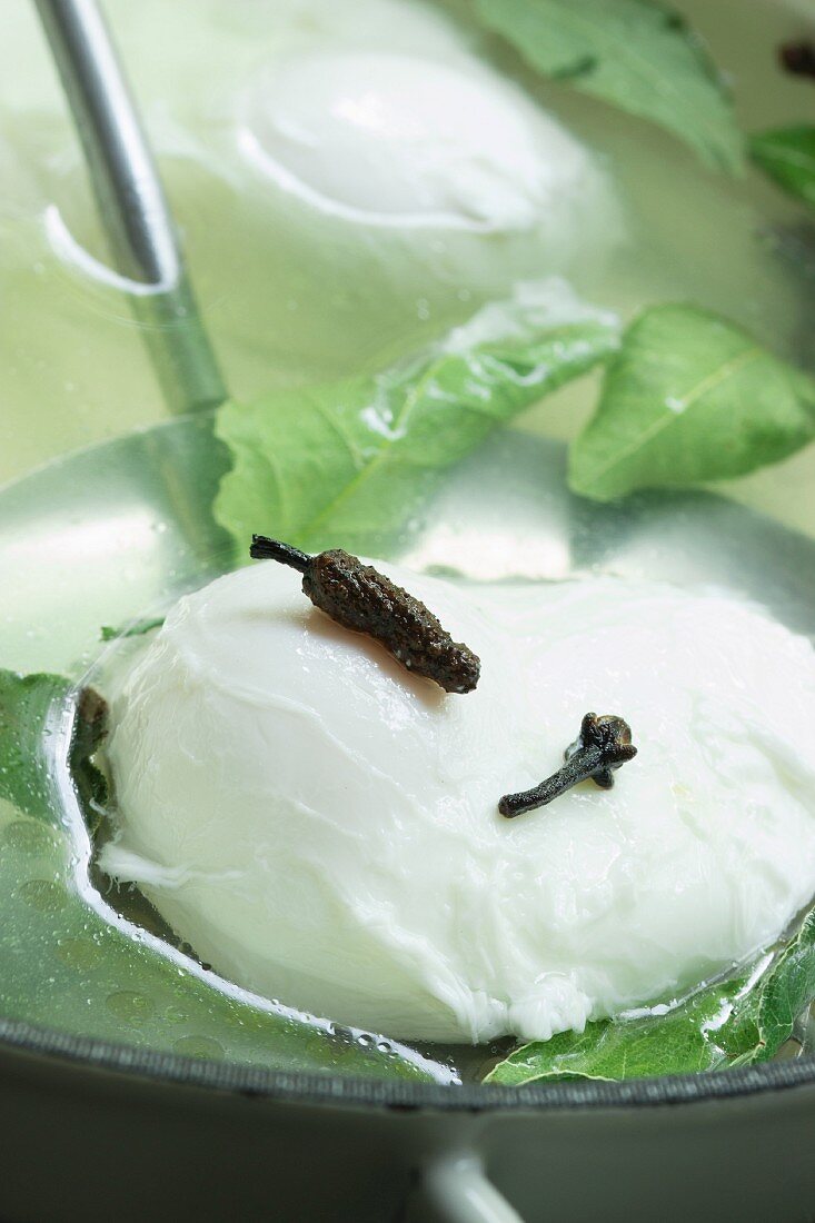 A poached egg on a draining spoon with spices