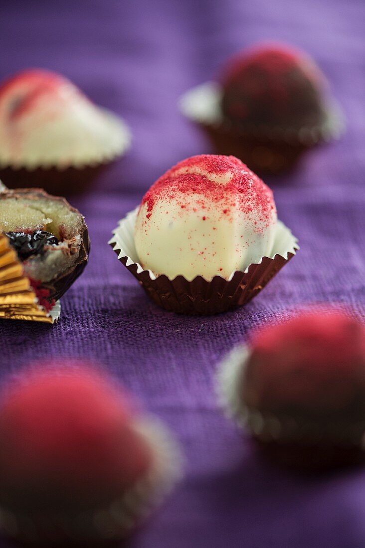 Cherry-marzipan bites with dark and white chocolate glaze and cherry powder