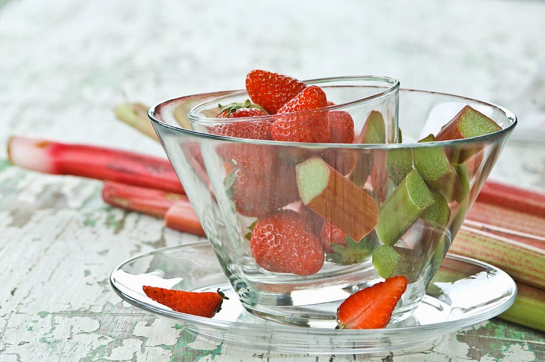 Rhabarberstücke und Erdbeeren in Glasschüsselchen auf Holztisch