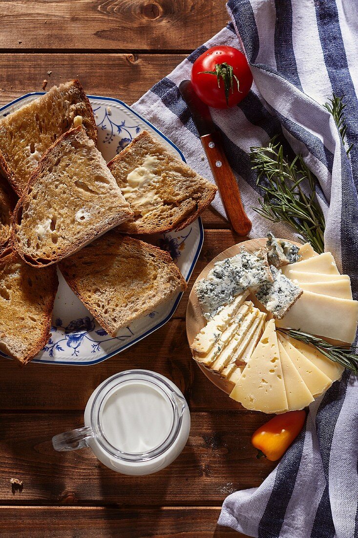 Käseteller, getoastete Brotscheiben und Milch (Draufsicht)