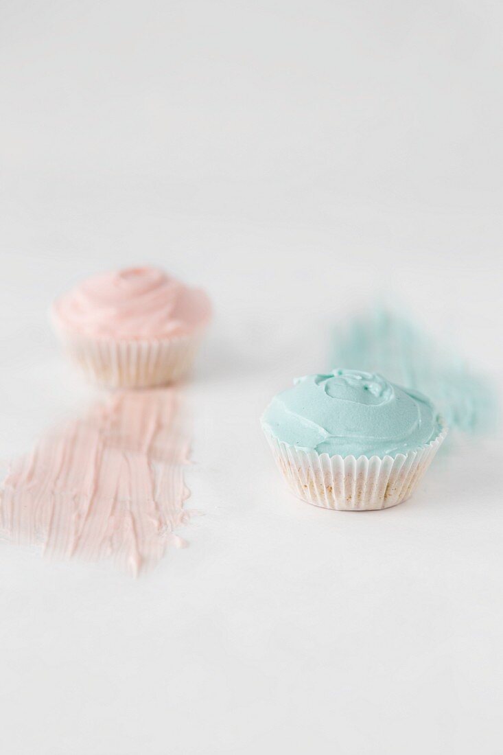 Zwei Cupcakes mit rosa und blauer Glasur