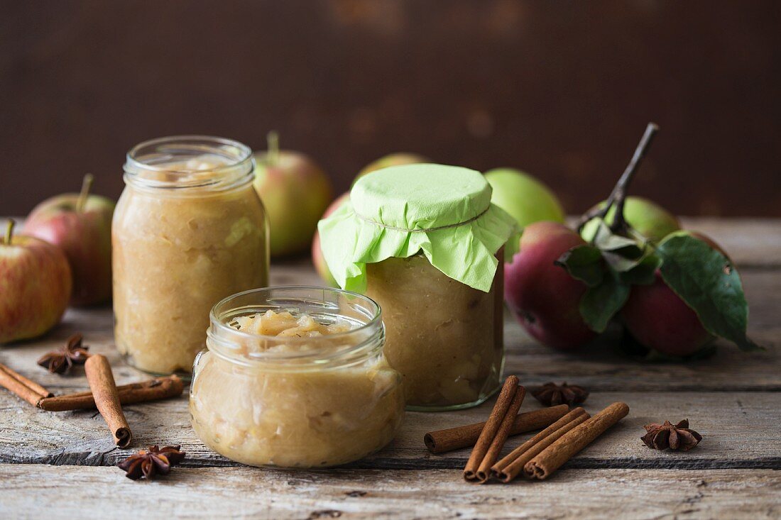 Jars of apple sauces, spices and fresh apples