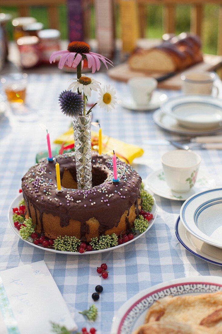 A birthday cake decorated with candles on a garden table