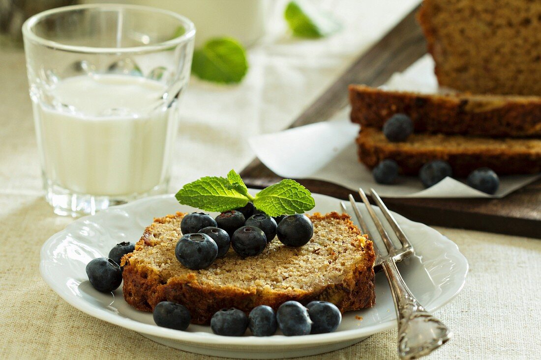 Sliced banana bread with blueberries and a glass of milk