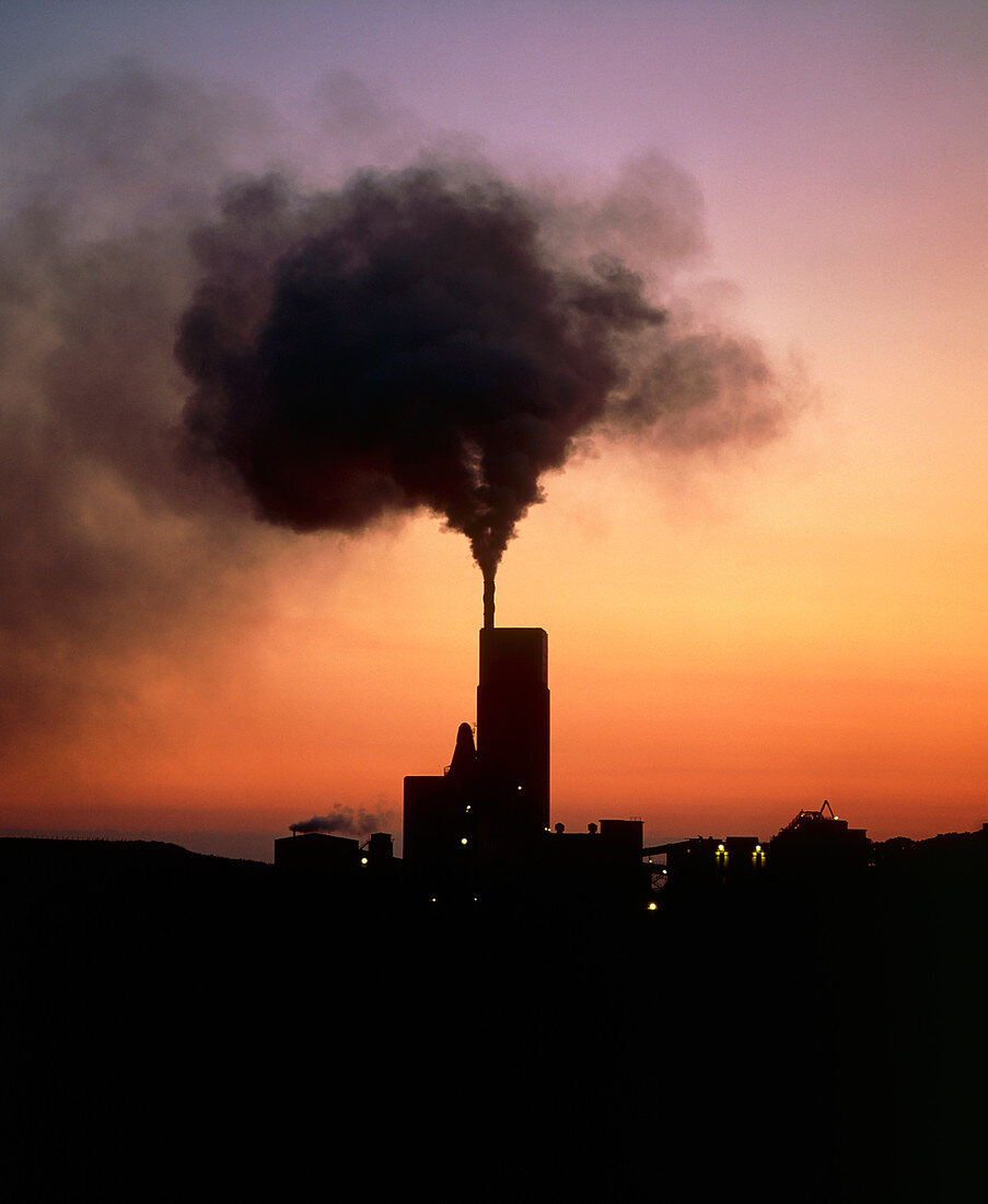 Polluting smoke from cement works chimney at dusk
