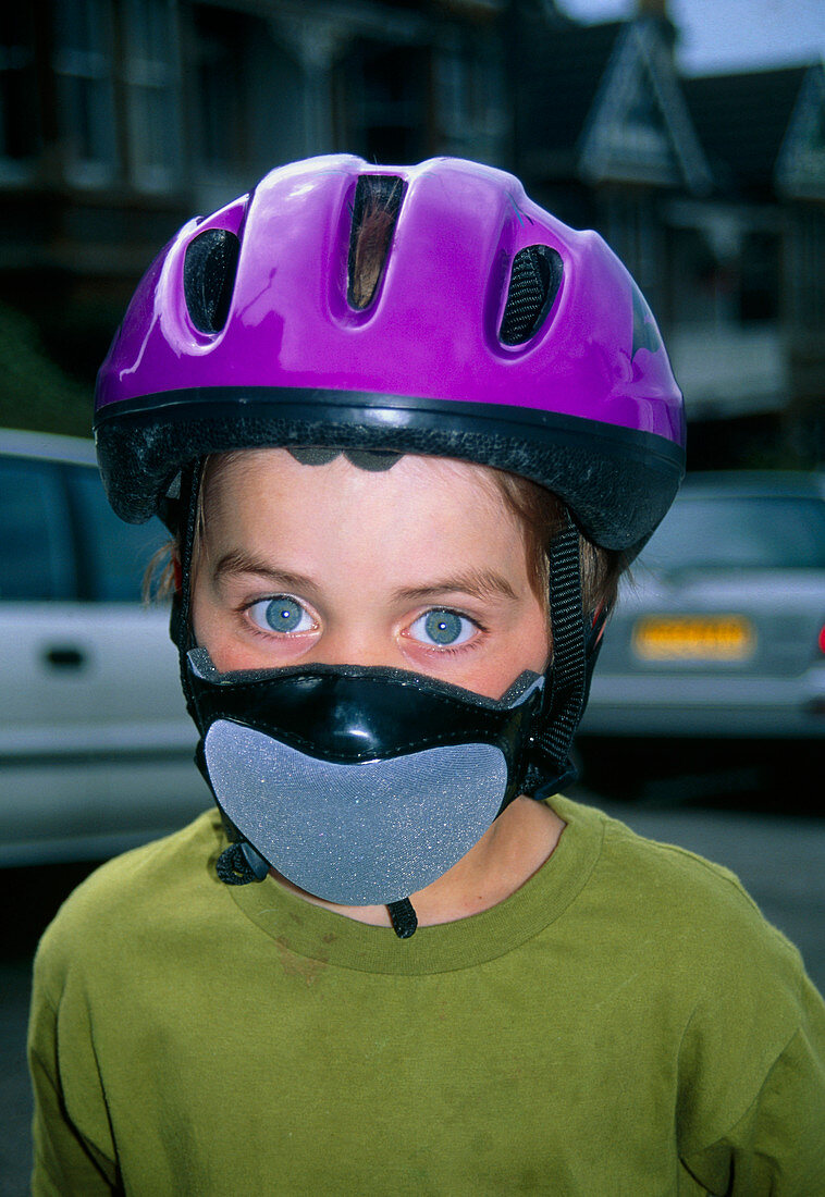 Child cyclist with helmet and anti-pollution mask