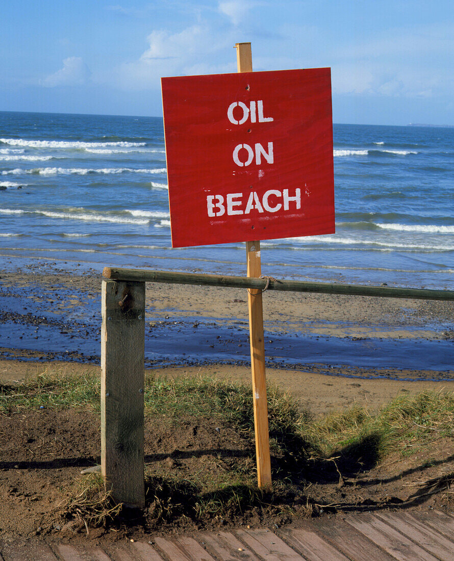 Sign warning on beach polluted by oil