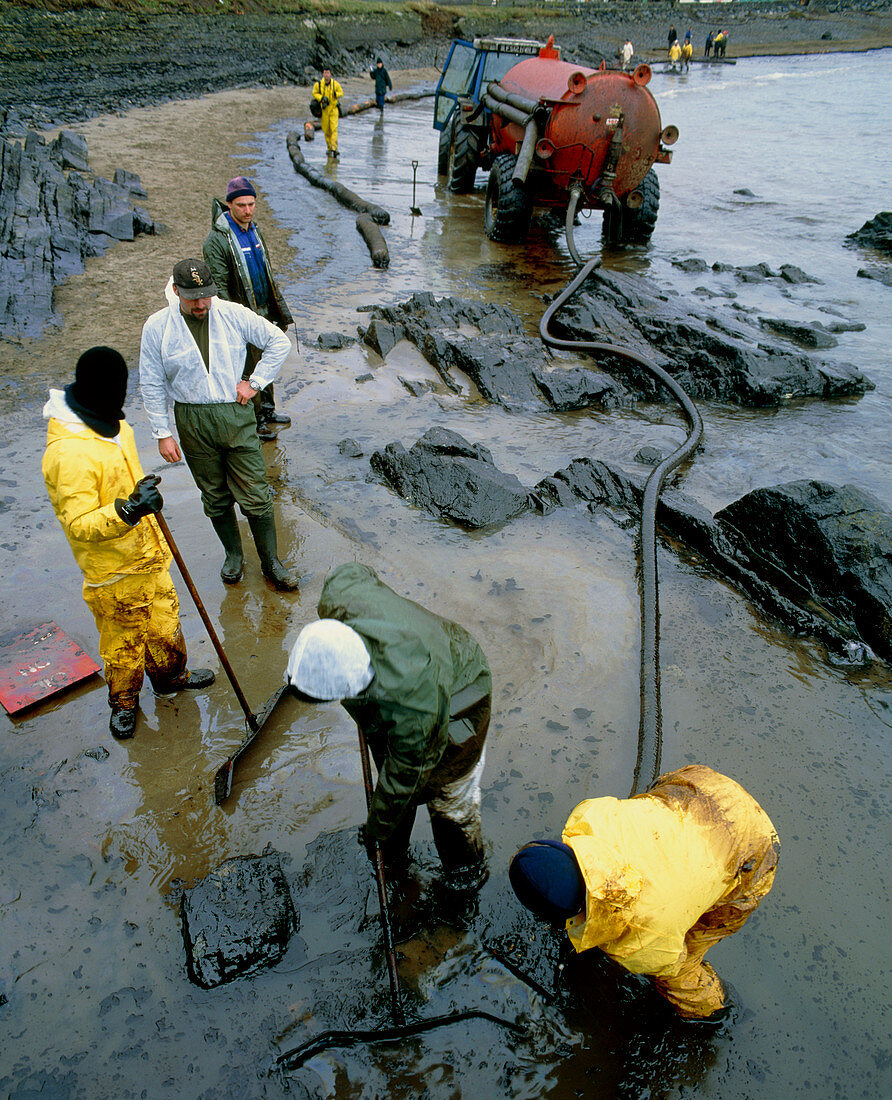 Workers cleaning up an oil slick on a beach