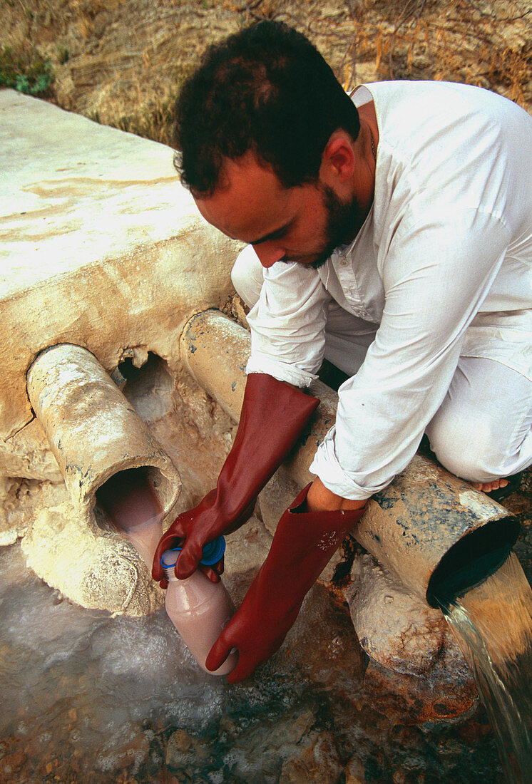 Scientist takes a sample from a water outflow pipe