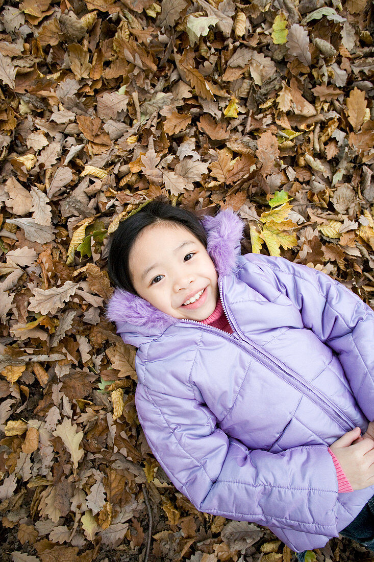 Smiling girl lying on autumn leaves