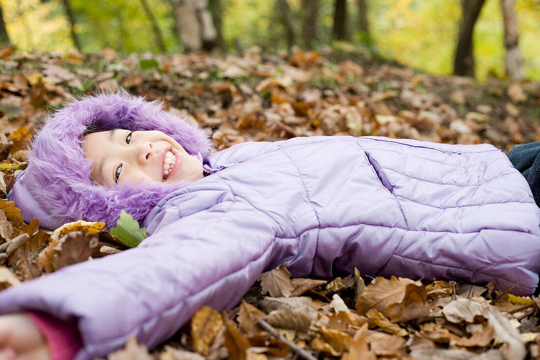 Smiling girl lying on autumn leaves