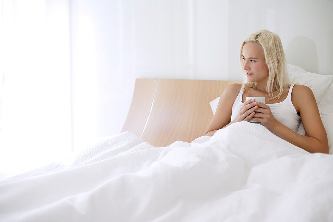 Woman drinking tea in bed