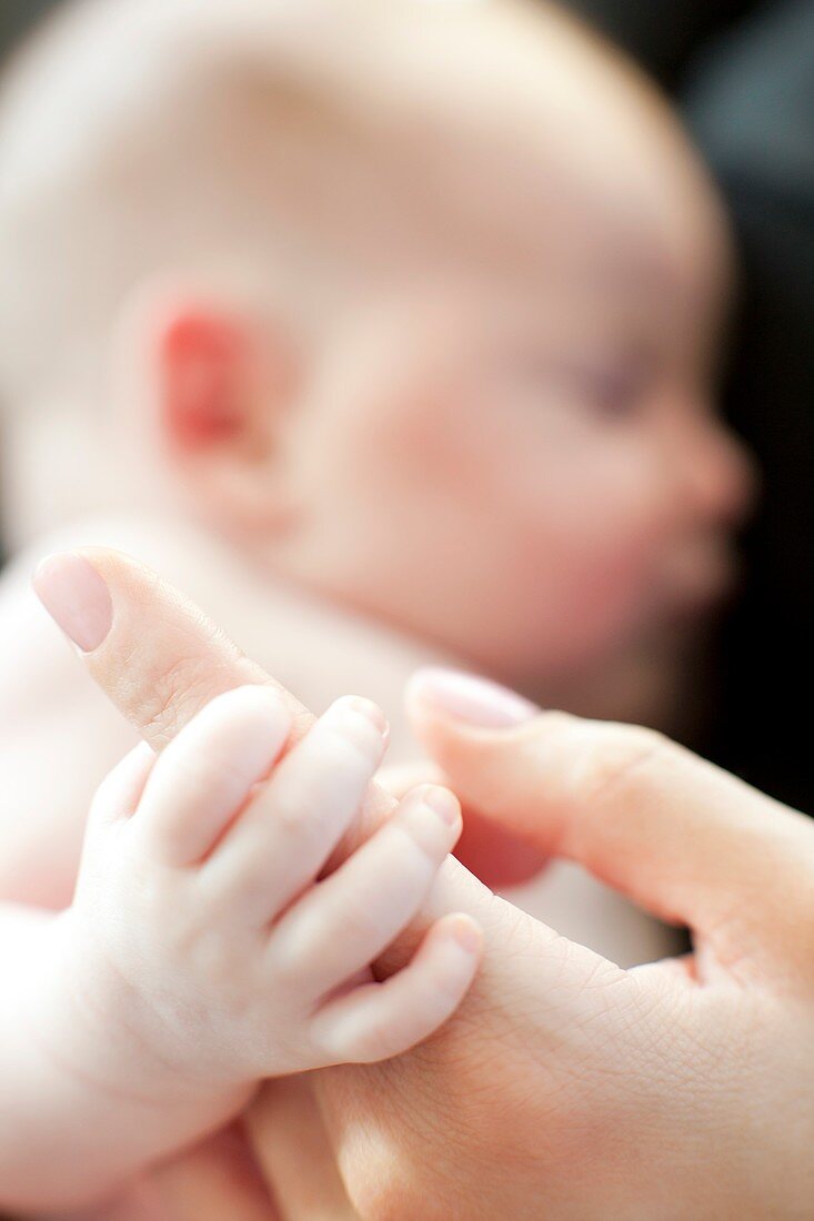 Baby grasping her mother's finger