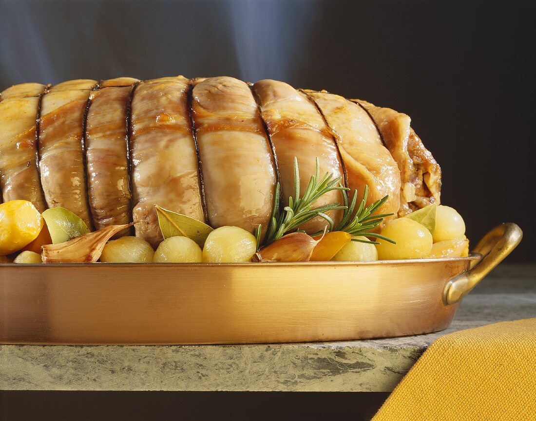 Roast veal roll with herbs & pearl onions in roasting tin