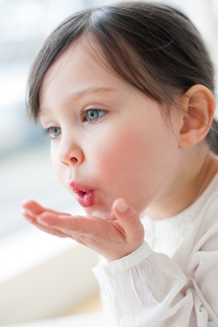 Three year old girl blowing a kiss