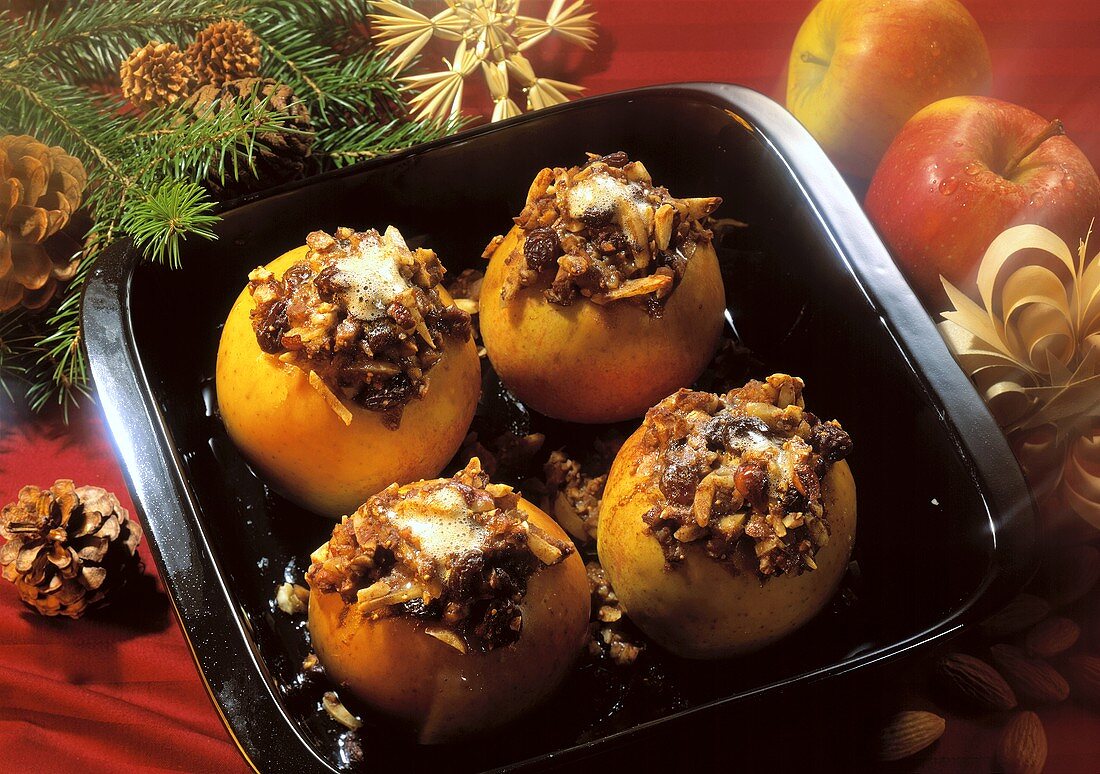Four baked apples stuffed with raisins and nuts in a baking dish