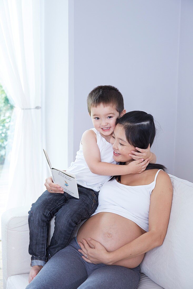 Pregnant woman reading to son