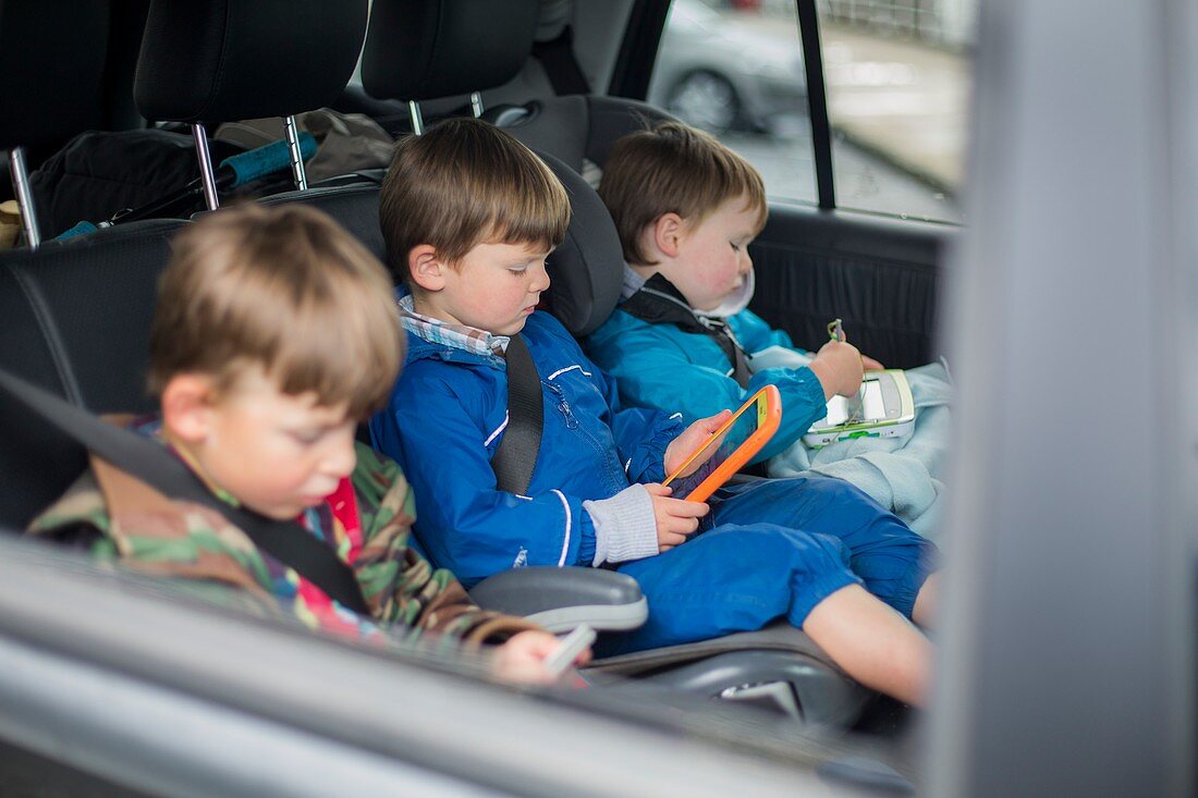 Three brothers in car with digital device