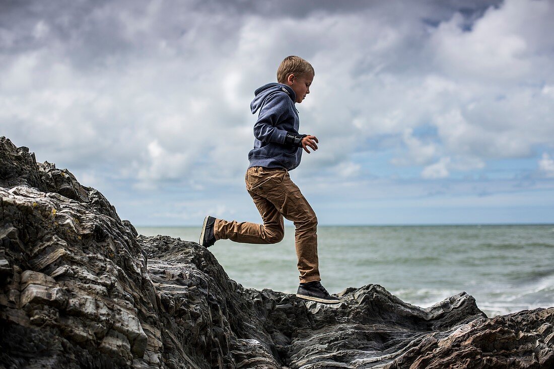 Young boy playing on rocks on beach
