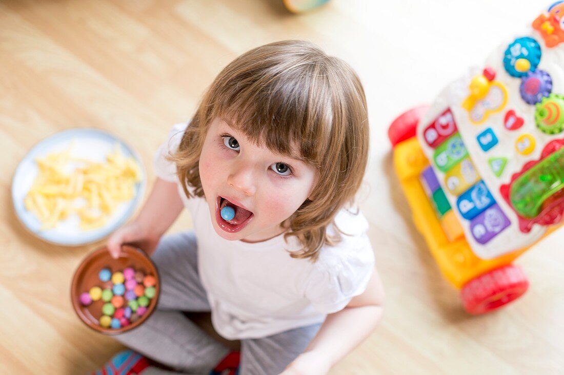 Girl sitting on floor with bowl of sweets