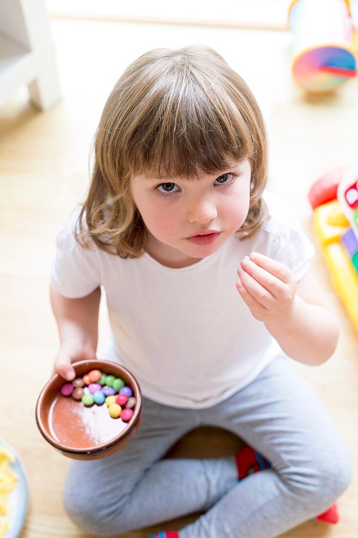 Girl sitting on floor with bowl of sweets