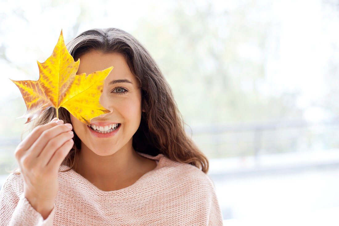 Woman holding leaf in front of face
