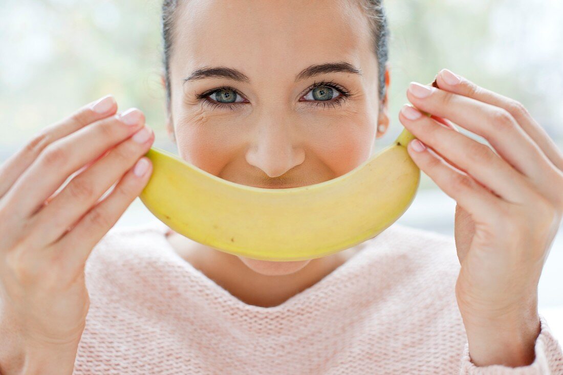 Woman holding a banana in front of face