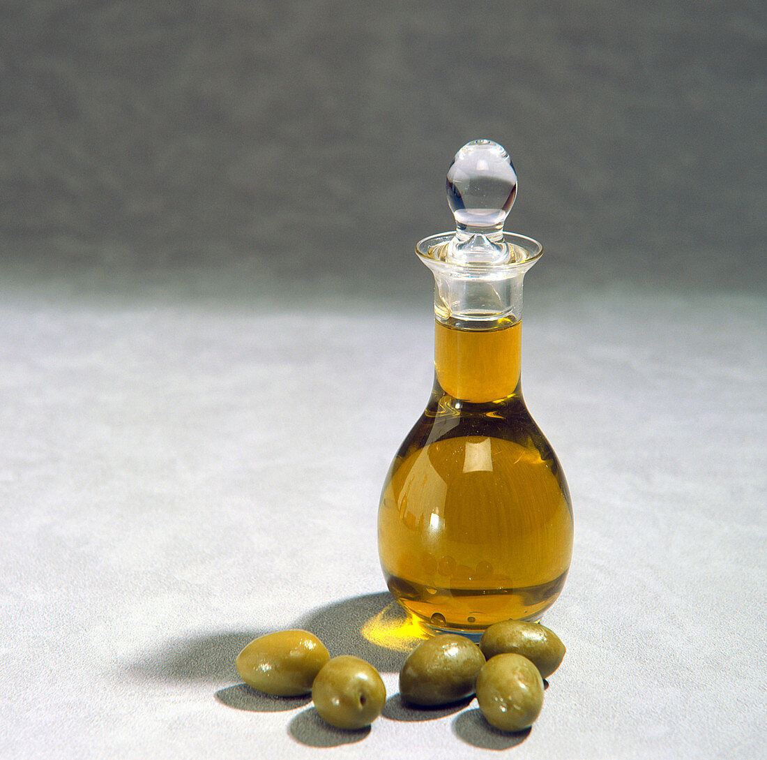 A decanter of olive oil,with olives