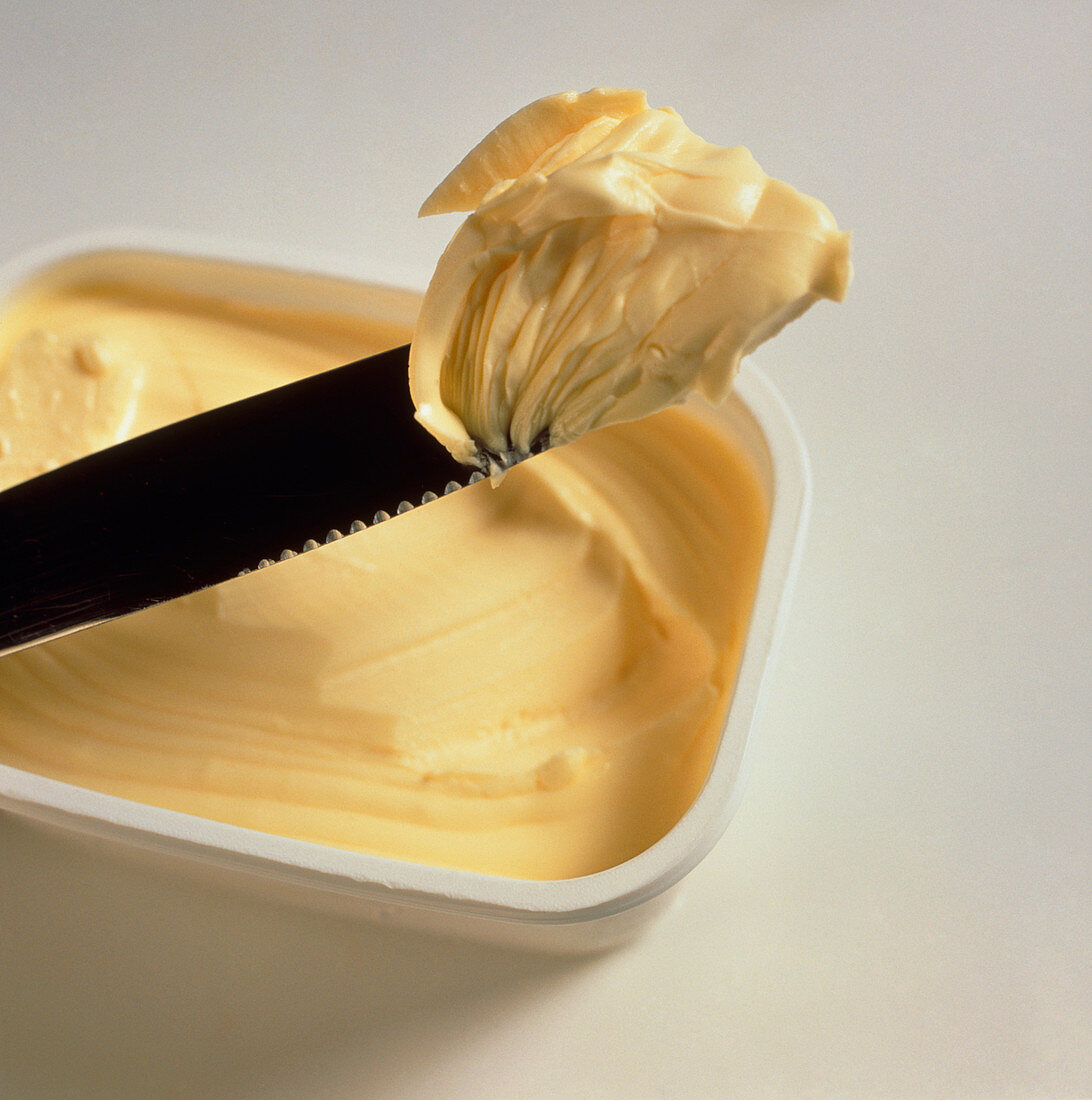 Knife scoops margarine from a tub