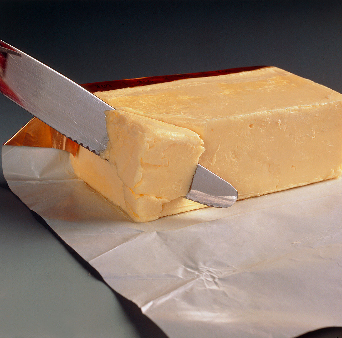 Block of butter being cut with a knife