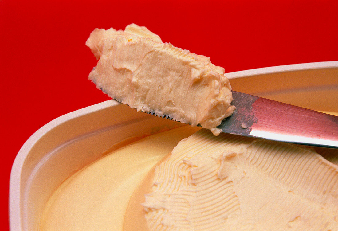 Knife scoops margarine from a tub
