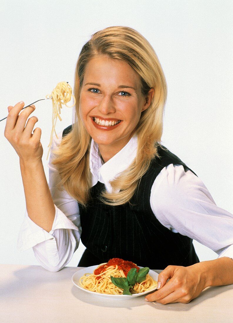 Young woman eating spaghetti with tomato sauce
