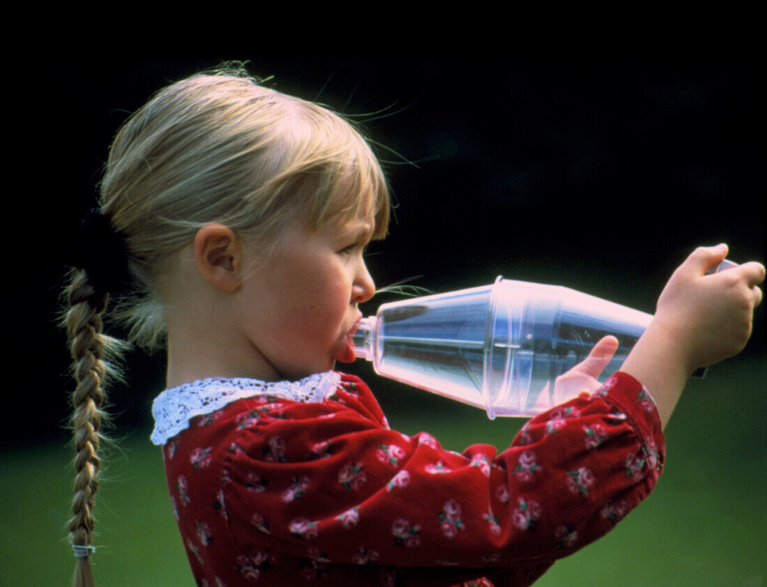 Young girl with asthma uses an inhaler adaptor