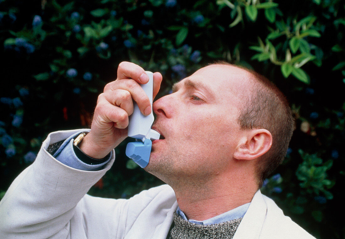Man using an aerosol inhaler to treat his asthma