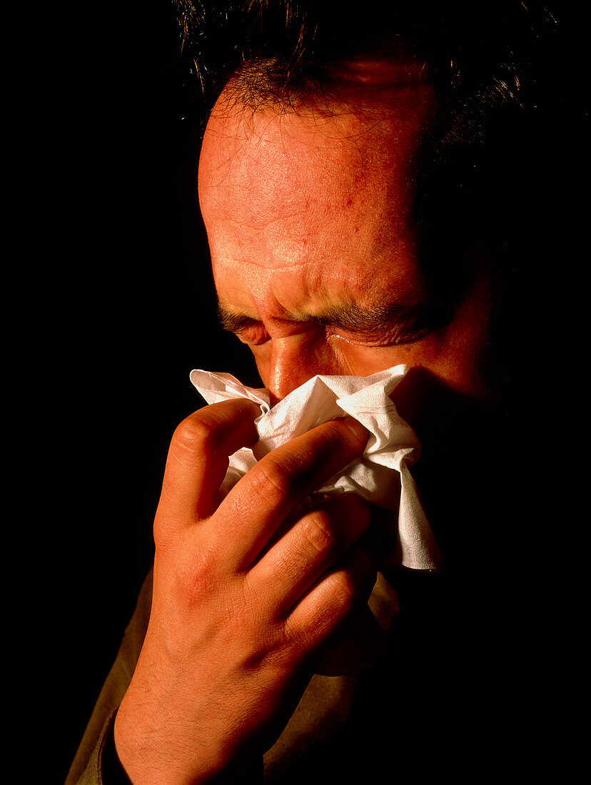 Man blowing his nose suffering from rhinitis