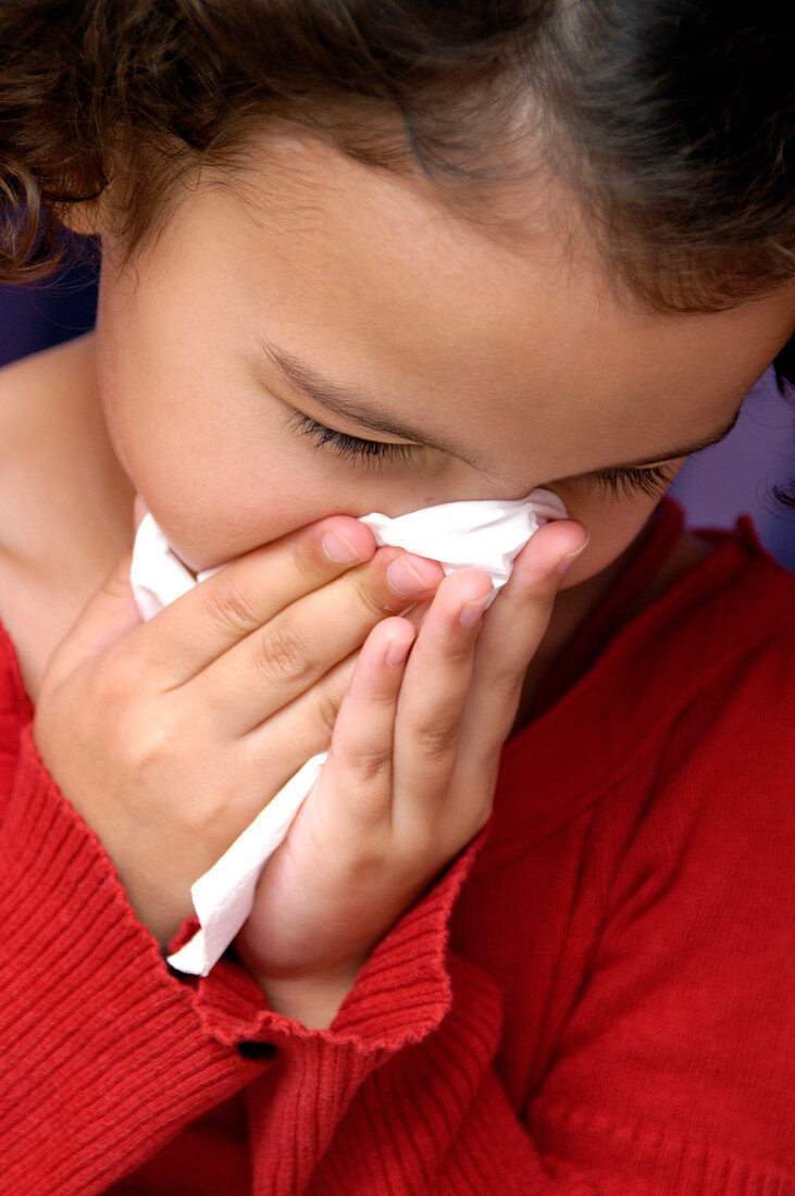 Young girl blowing her nose