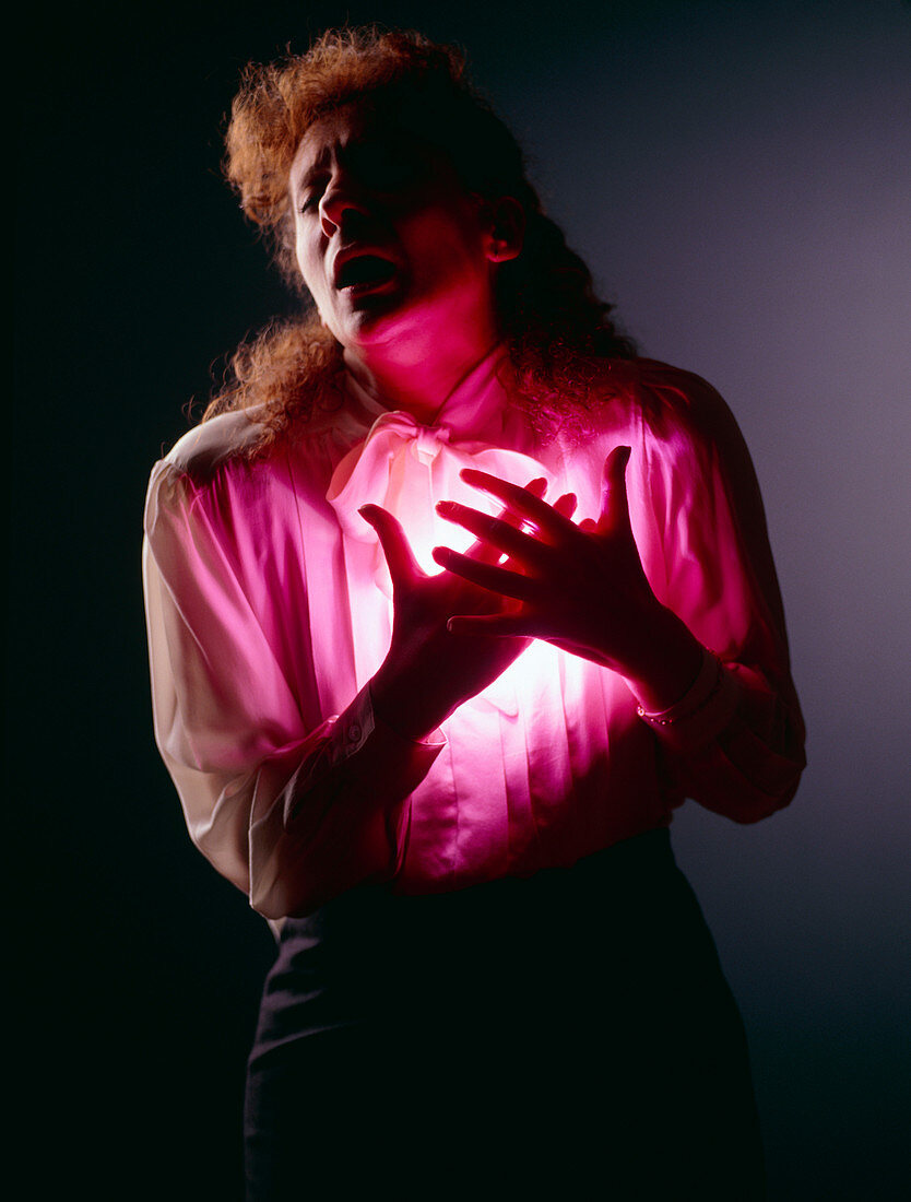 Woman holding her chest in angina or heart attack