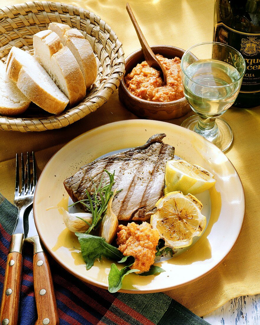 Grilled tuna steak with spicy dip and lemons