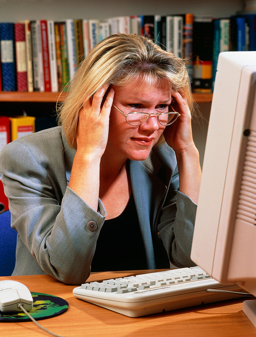 Stressed and tired woman at an office computer