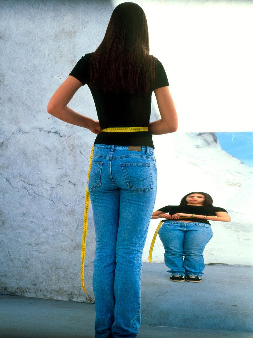 Anorexic teenage girl measuring herself in mirror