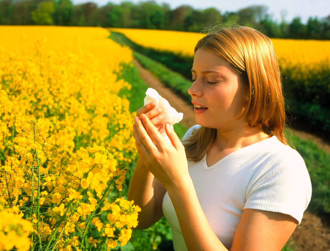 Young woman suffering from hay fever in a field