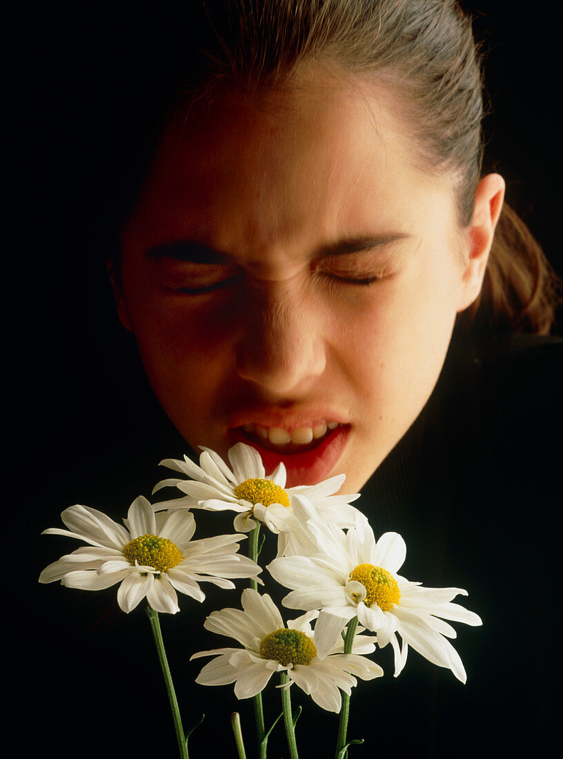 Teenage girl suffering from hay fever near flowers