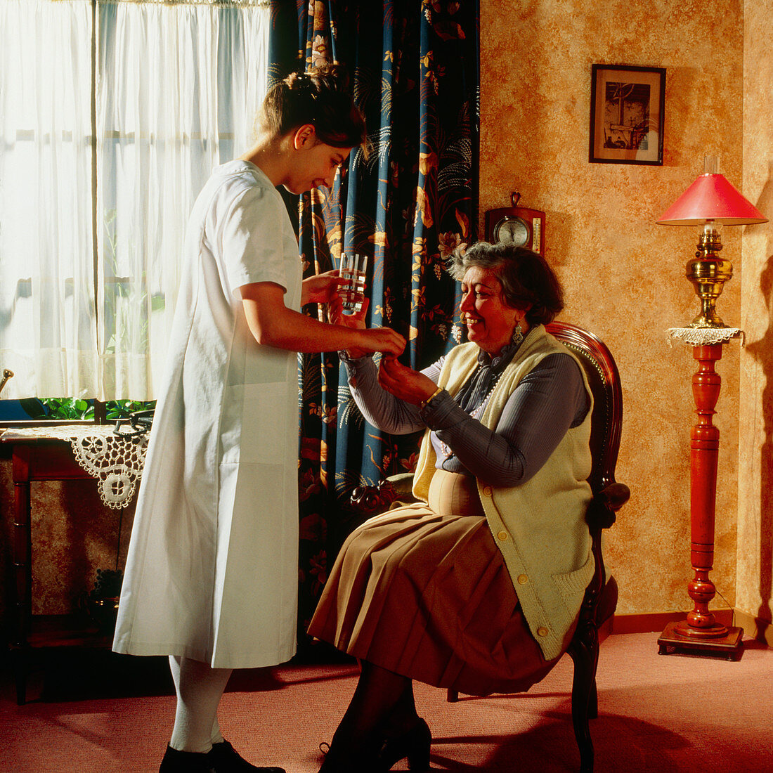 Nurse gives elderly woman her medication at home
