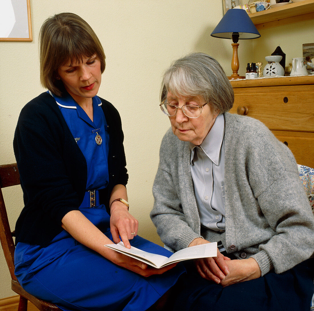District nurse shows information book to old woman