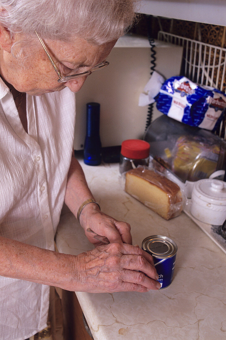 Elderly woman using tin-opener