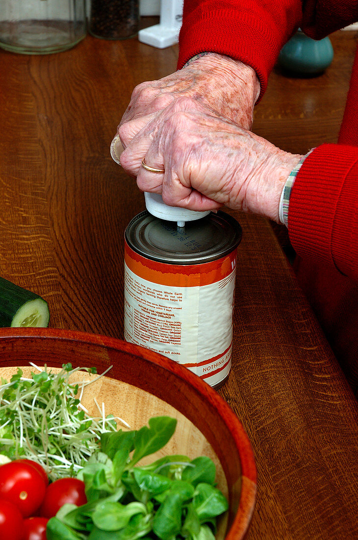 Elderly person opening a can of food