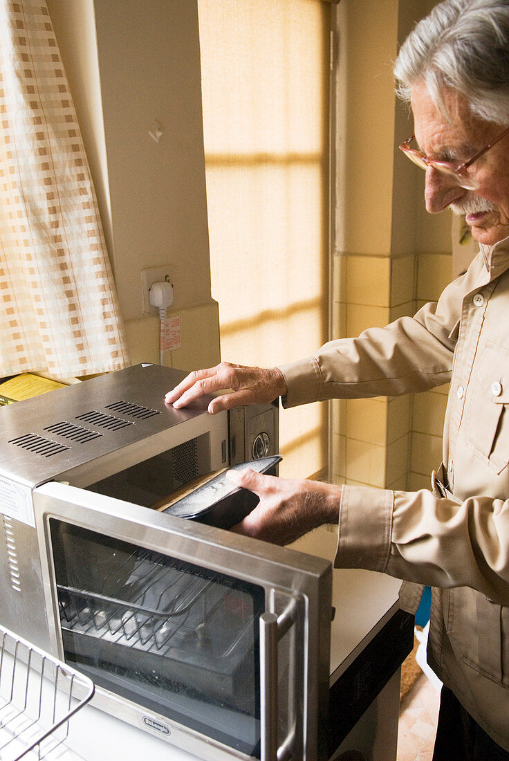 Elderly man using a microwave oven