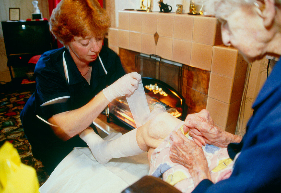 District nurse bandages elderly woman's leg ulcer