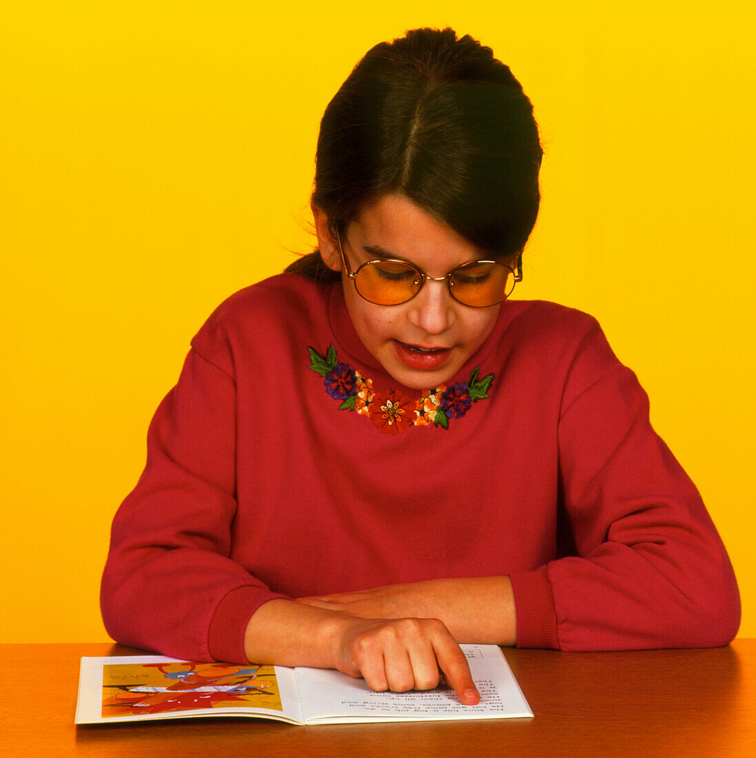 Dyslexic girl wears Irlen lenses to read a book